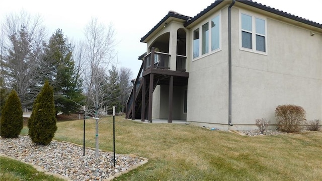 rear view of property with a yard, a patio, a balcony, and a tiled roof