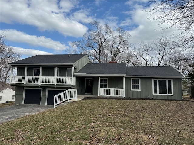 tri-level home featuring a chimney, aphalt driveway, covered porch, board and batten siding, and a front yard