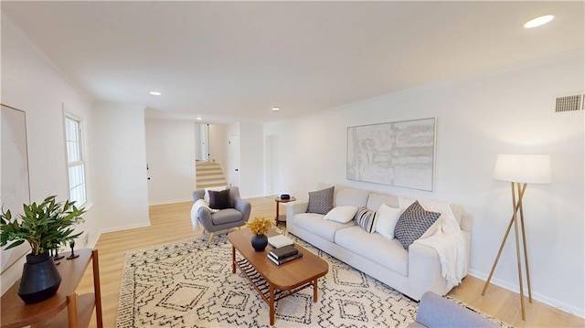 living room with light wood-style flooring, stairway, visible vents, and baseboards