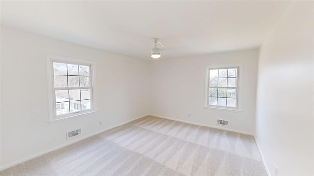 spare room featuring light carpet, visible vents, and baseboards