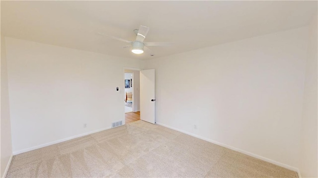 spare room with baseboards, a ceiling fan, visible vents, and light colored carpet