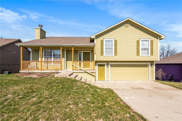 split level home featuring a front lawn, driveway, covered porch, an attached garage, and a chimney