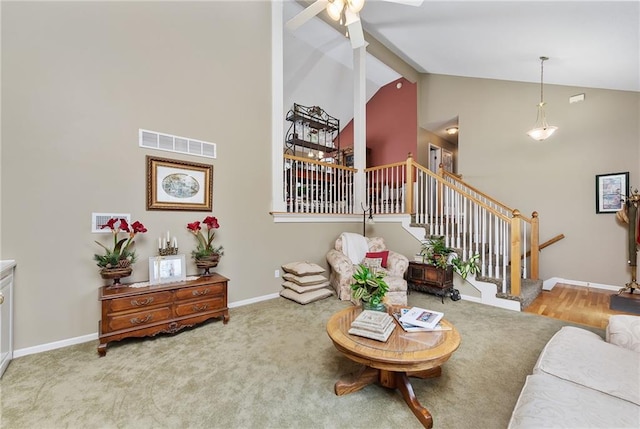 carpeted living area with visible vents, high vaulted ceiling, a ceiling fan, stairway, and baseboards