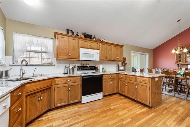 kitchen featuring white appliances, brown cabinetry, a peninsula, light wood-style flooring, and a sink