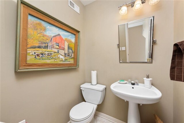 half bath with visible vents, toilet, and baseboards