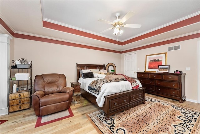 bedroom featuring visible vents, light wood-style floors, ornamental molding, and ornate columns