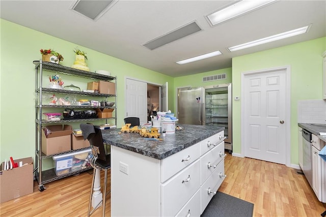 kitchen with appliances with stainless steel finishes, white cabinets, a center island, and light wood finished floors