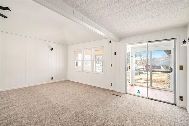 carpeted empty room featuring baseboards, visible vents, vaulted ceiling with beams, and a ceiling fan