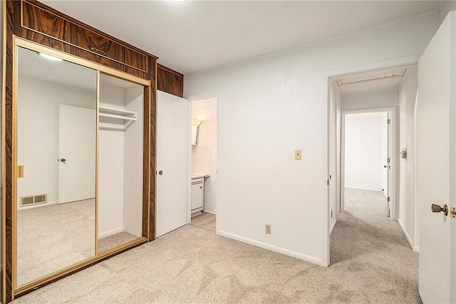 unfurnished bedroom with visible vents, baseboards, light colored carpet, attic access, and a closet