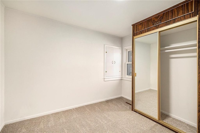 unfurnished bedroom featuring a closet, baseboards, and light colored carpet