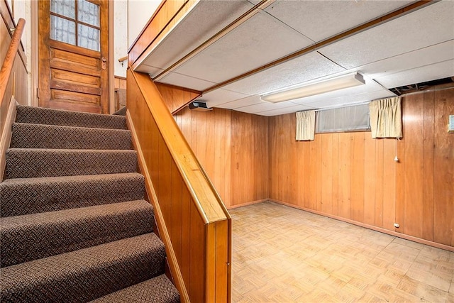 stairs with wooden walls and a drop ceiling