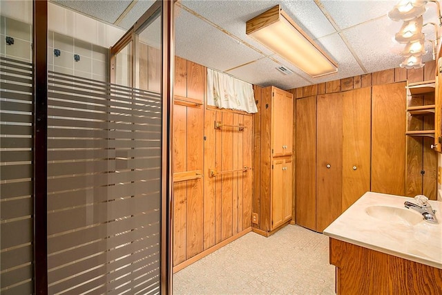 bathroom featuring tile patterned floors, wood walls, and vanity