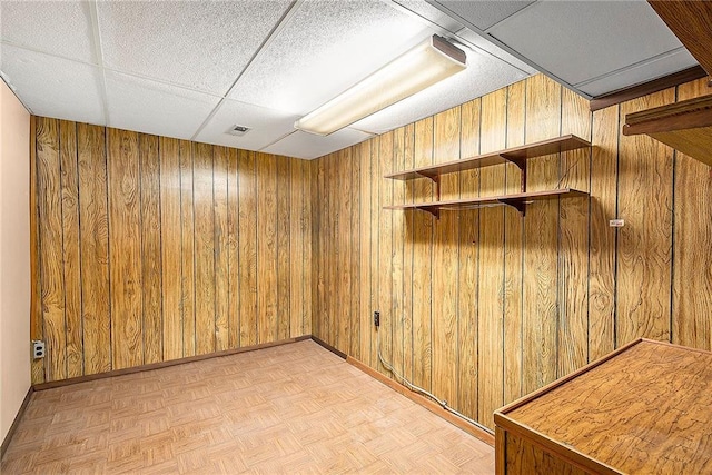 empty room featuring visible vents, baseboards, and wooden walls