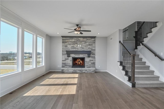 unfurnished living room with a fireplace, visible vents, stairway, a ceiling fan, and wood finished floors