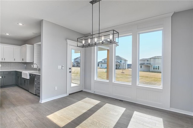 unfurnished dining area featuring baseboards, visible vents, and wood finished floors