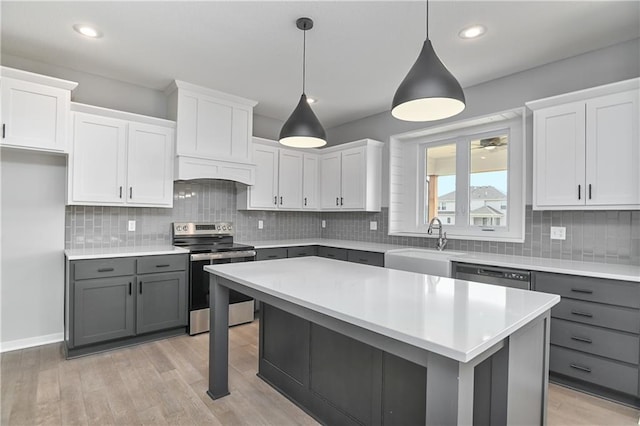 kitchen featuring gray cabinetry, a sink, light countertops, appliances with stainless steel finishes, and light wood finished floors