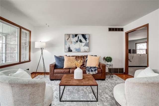 living area with wood finished floors, visible vents, and baseboards