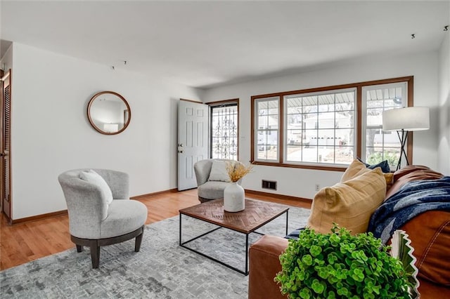 living area with light wood-type flooring, visible vents, and baseboards