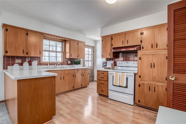 kitchen featuring light wood-style floors, tasteful backsplash, under cabinet range hood, and white range with electric cooktop