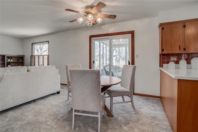 dining area with light colored carpet, baseboards, and ceiling fan