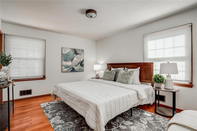 bedroom featuring visible vents, baseboards, and wood finished floors