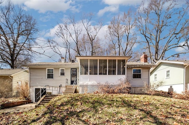 rear view of house featuring stairway, a chimney, and a sunroom