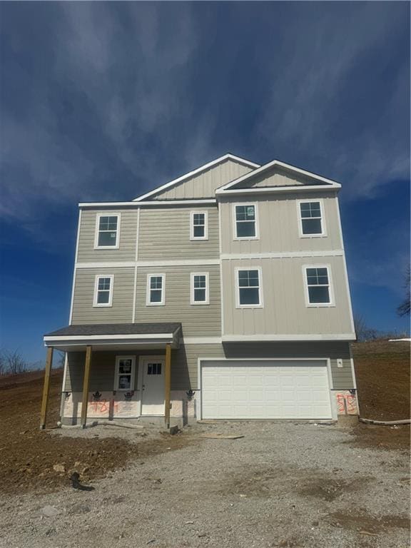 view of front of house featuring dirt driveway, covered porch, board and batten siding, and an attached garage