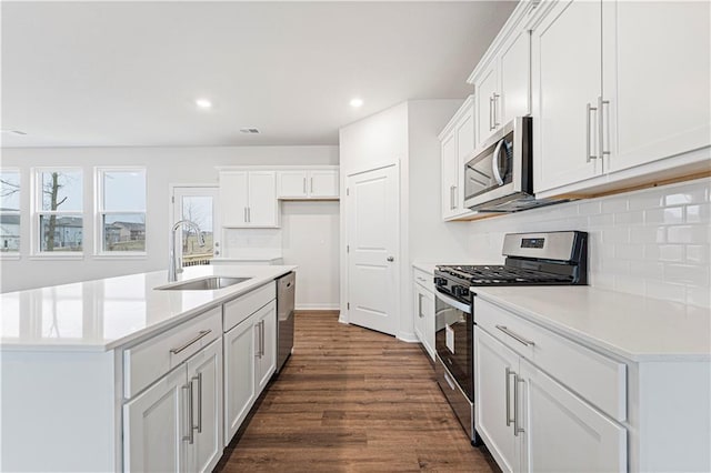 kitchen featuring visible vents, decorative backsplash, appliances with stainless steel finishes, dark wood-style flooring, and a sink