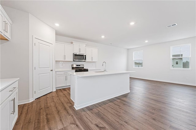 kitchen with stainless steel appliances, light countertops, dark wood finished floors, and visible vents