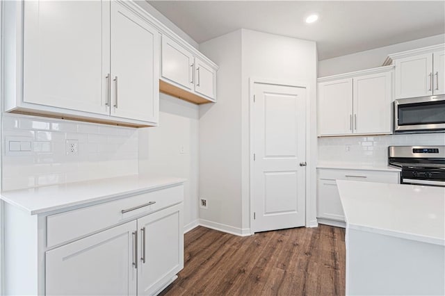 kitchen featuring appliances with stainless steel finishes, light countertops, white cabinetry, and dark wood-style floors
