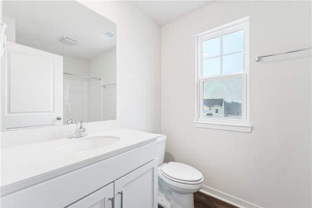 bathroom featuring baseboards, visible vents, toilet, wood finished floors, and vanity