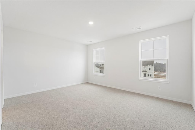 carpeted empty room with a healthy amount of sunlight, baseboards, visible vents, and recessed lighting