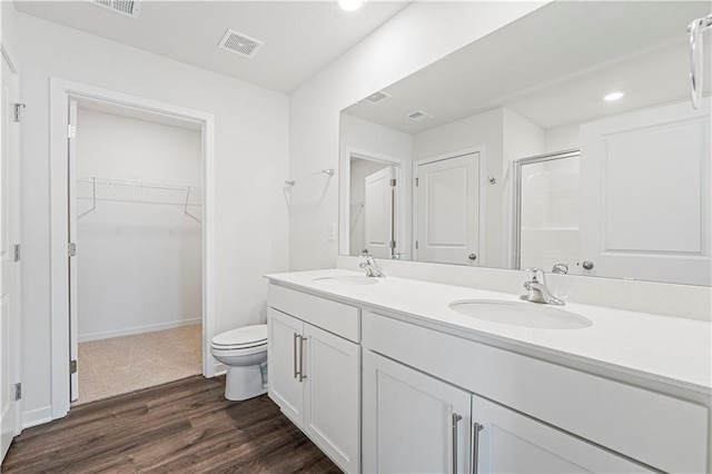 bathroom with visible vents, a sink, a shower stall, and wood finished floors