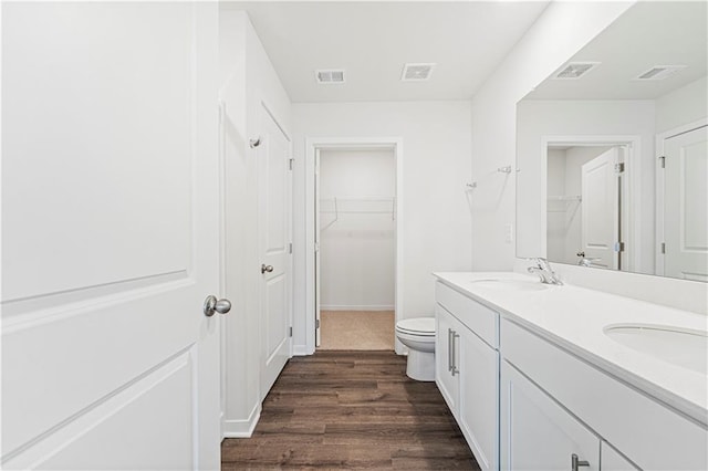 bathroom with double vanity, visible vents, a sink, and wood finished floors