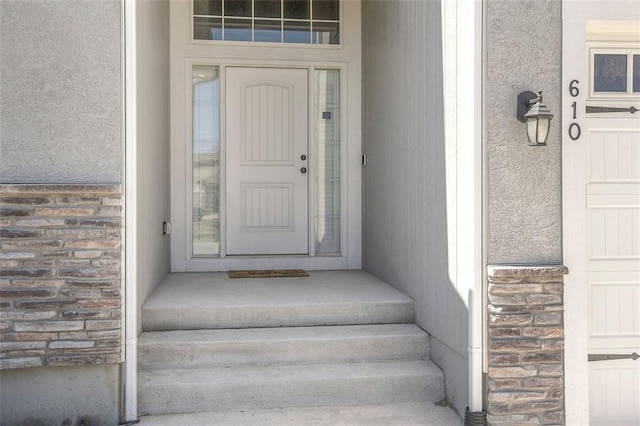 view of exterior entry with a garage and stone siding