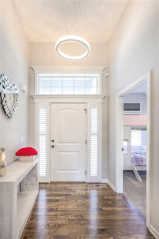 foyer featuring dark wood-style floors, a towering ceiling, and baseboards