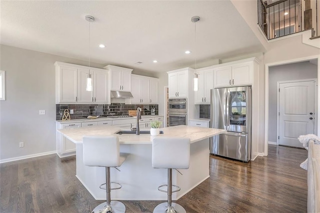 kitchen with light countertops, appliances with stainless steel finishes, dark wood finished floors, and under cabinet range hood