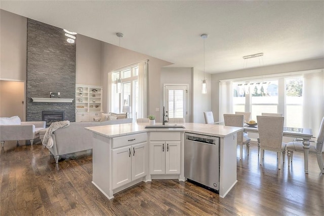 kitchen featuring a stone fireplace, dark wood-type flooring, a sink, light countertops, and stainless steel dishwasher