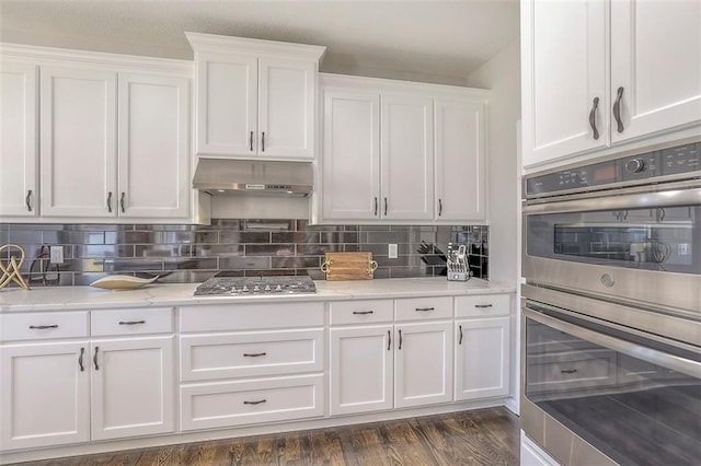 kitchen featuring stainless steel appliances, decorative backsplash, dark wood-type flooring, white cabinets, and under cabinet range hood