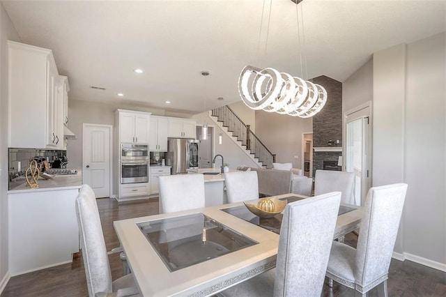 dining area with baseboards, stairway, dark wood-style flooring, a fireplace, and recessed lighting