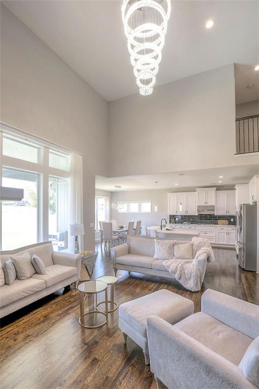 living room featuring dark wood-style floors, a chandelier, and a towering ceiling