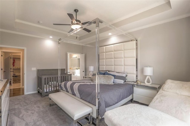 carpeted bedroom featuring a ceiling fan, a raised ceiling, crown molding, and baseboards