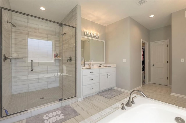 bathroom with a garden tub, vanity, baseboards, a spacious closet, and a stall shower