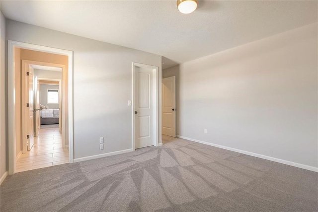 unfurnished bedroom with baseboards, a textured ceiling, and light colored carpet