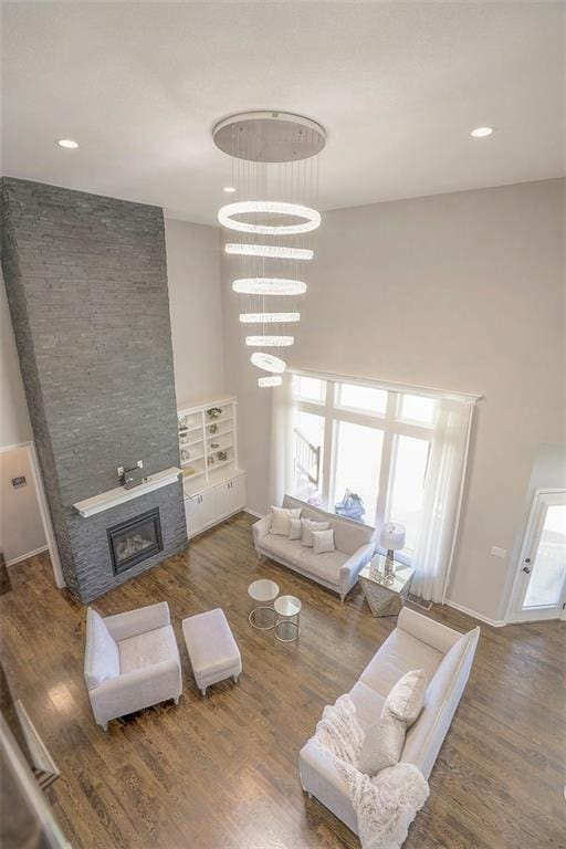 living area featuring a fireplace, wood finished floors, a wealth of natural light, and an inviting chandelier