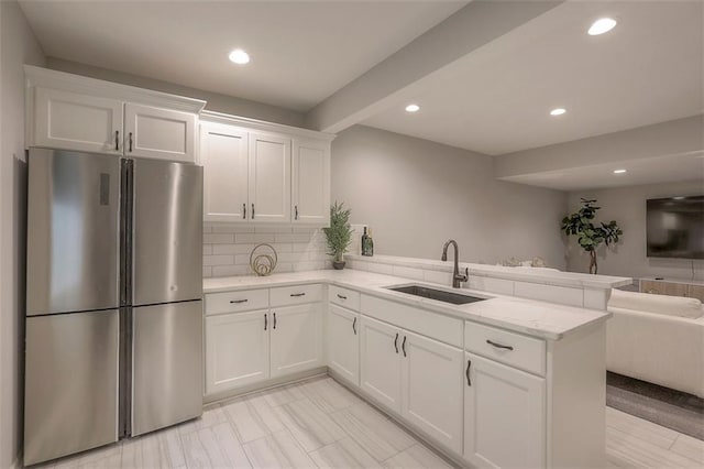 kitchen with freestanding refrigerator, open floor plan, white cabinets, a sink, and a peninsula