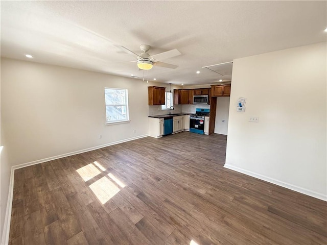 kitchen with appliances with stainless steel finishes, dark countertops, baseboards, and dark wood-style floors