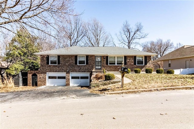 view of front of home with brick siding, driveway, an attached garage, and fence