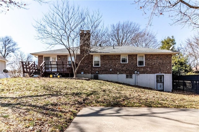 rear view of property featuring brick siding, a chimney, central air condition unit, fence, and a deck