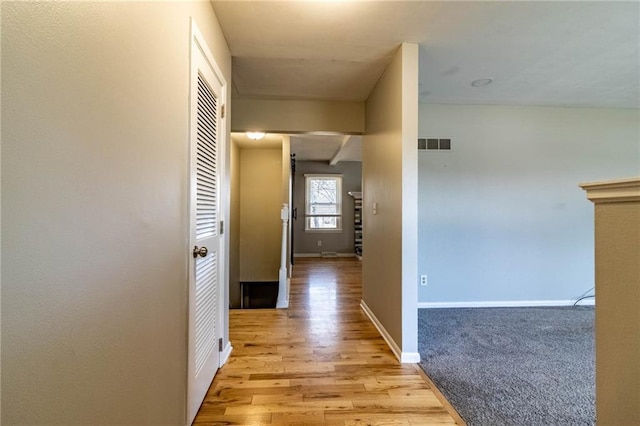 hall featuring light wood-style floors, baseboards, and visible vents